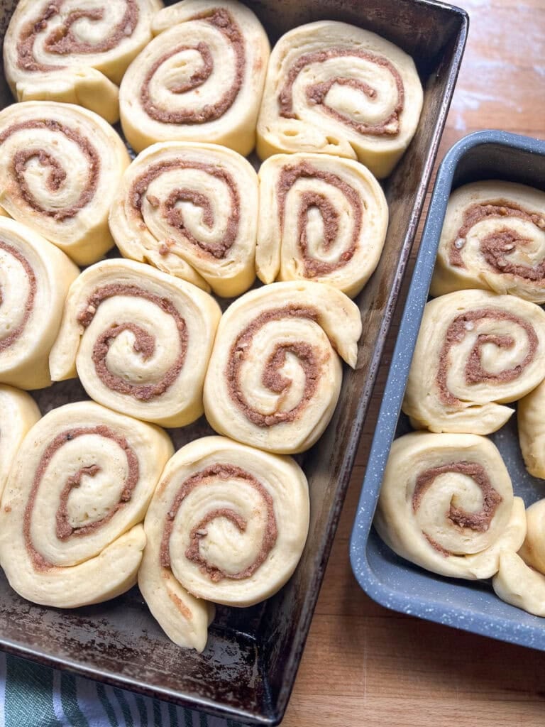 Unbaked pecan cinnamon rolls in baking pans that have had a second rise and are ready for the oven.