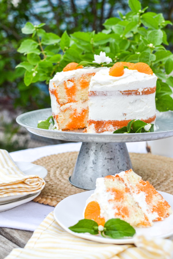 Double layered orange creamsicle poke cake with whipped cream and orange garnish