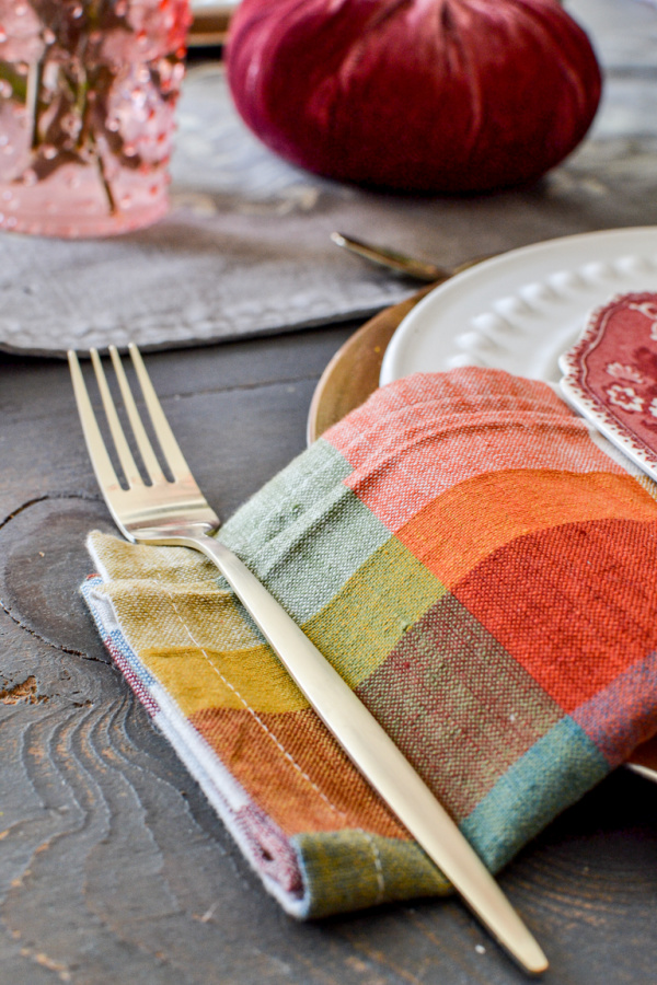 Gold flatware for an autumn tablescape on a plaid napkin in traditional all colours