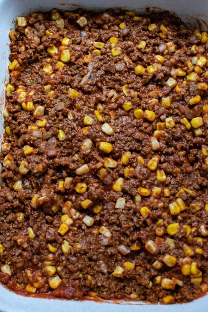 Ground beef taco mixture pressed into a casserole dish.