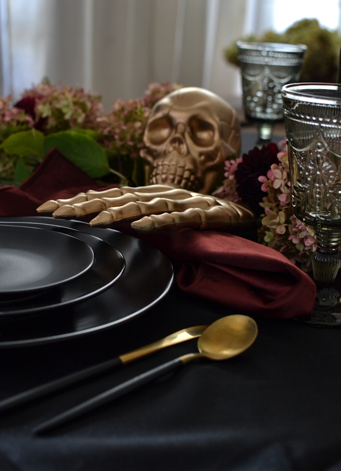 Gold skull and skeleton hand on a black Halloween table