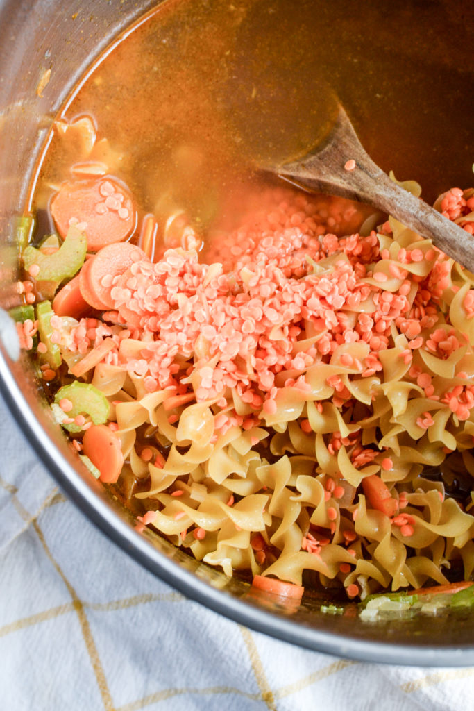 Noodles, lentils and broth added to vegetable noodle soup