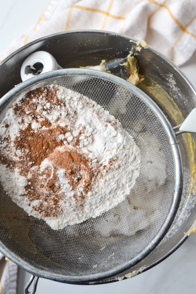 sifting flour and spices into the oatmeal cookie recipe