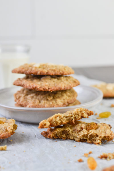 Oatmeal cookie broken in half beside a stack of cookies