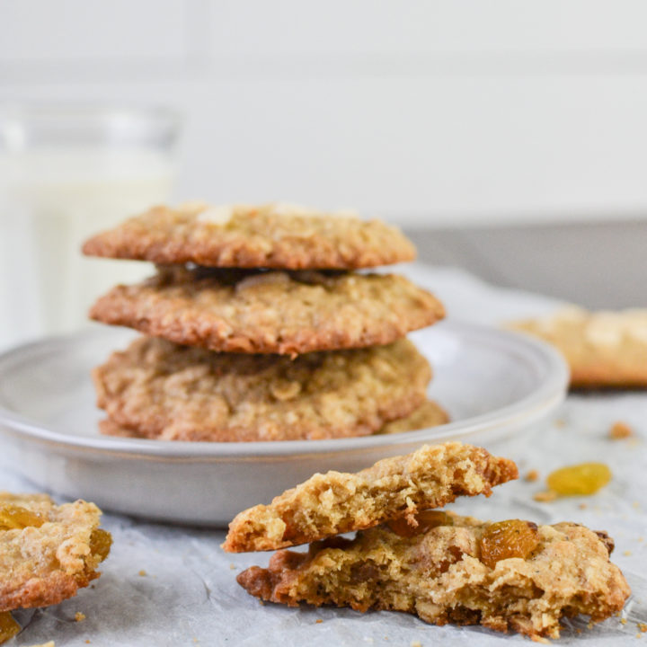 Oatmeal cookie broken in half beside a stack of cookies