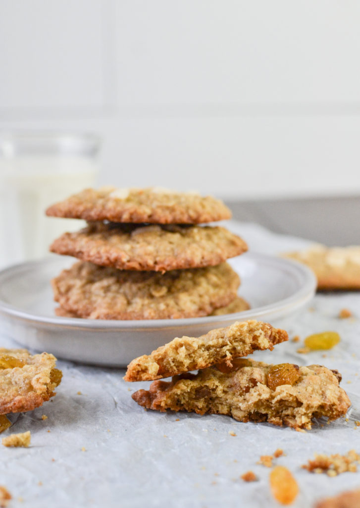 Oatmeal cookie broken in half beside a stack of cookies