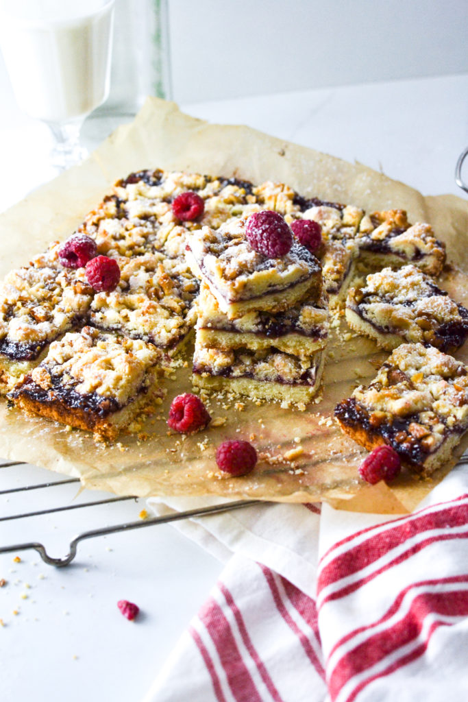 raspberry jam bars sliced into squares on a sheet of parchment