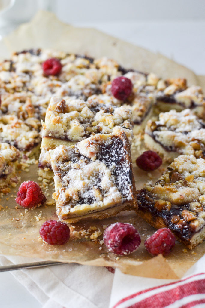 a raspberry jam bar set on its side to show off the jam filling and crumble top