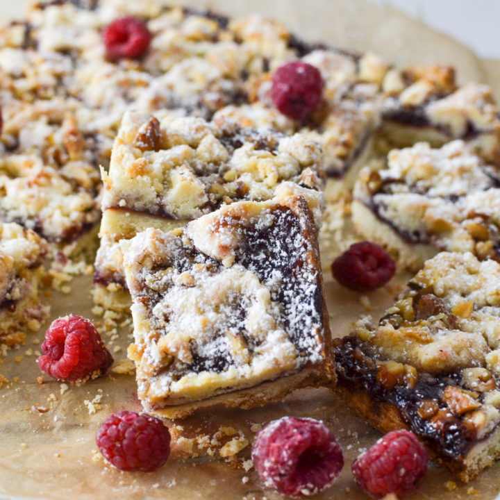 a raspberry jam bar set on its side to show off the jam filling and crumble top