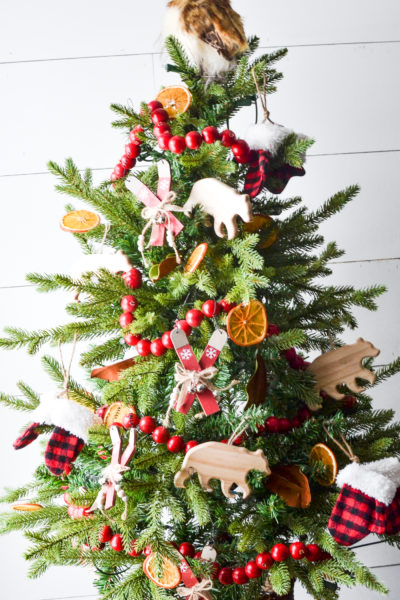 Cozy cabin Christmas tree with skis, dried orange slices, red berry garland and an owl on top