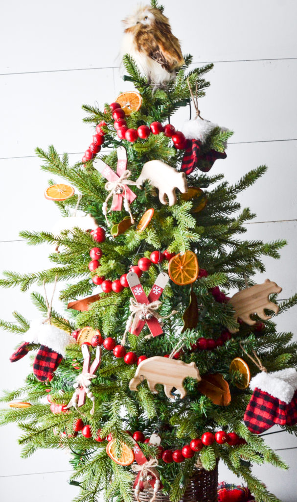 Cozy cabin Christmas tree with skis, dried orange slices, red berry garland and an owl on top