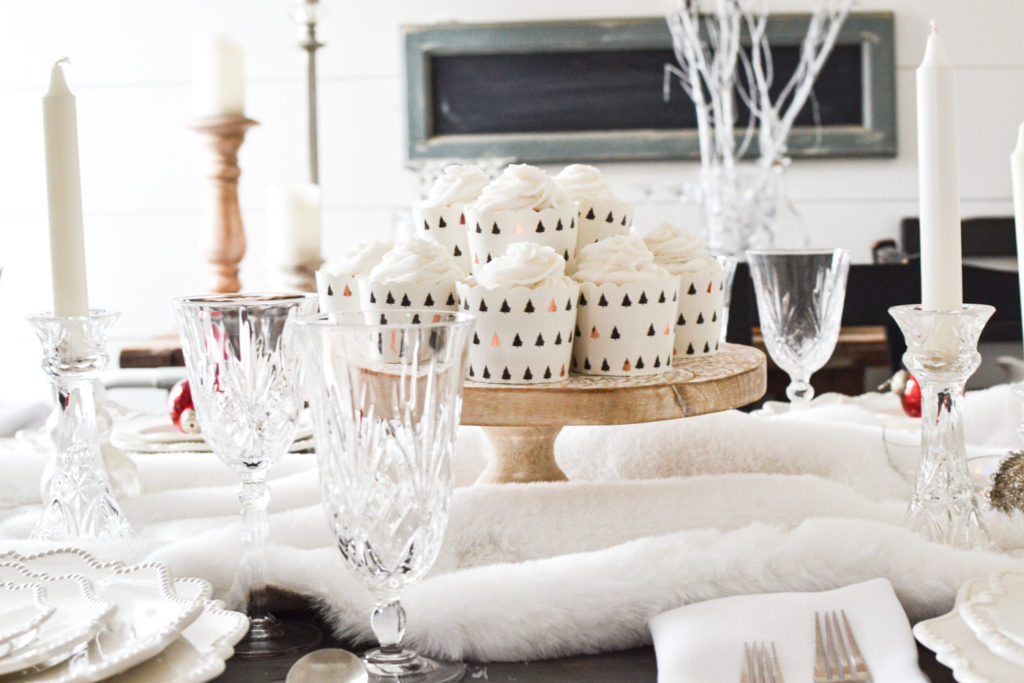 A centrepiece of white cupcakes on a wood cake stand