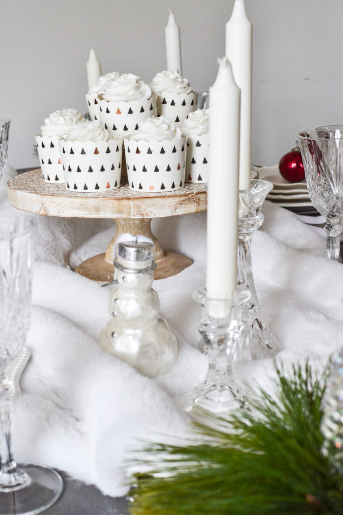 A wood cake stand with white cupcakes on A White Christmas tablescape