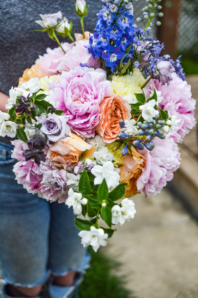 straight on view of a hand tied flower bouquet in pinks, violets, yellow and peach tones