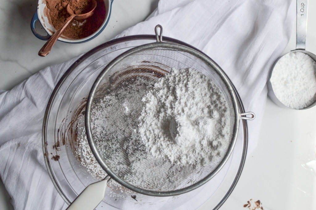 icing sugar sifted into melted butter and cocoa powder for marshmallow brownie frosting