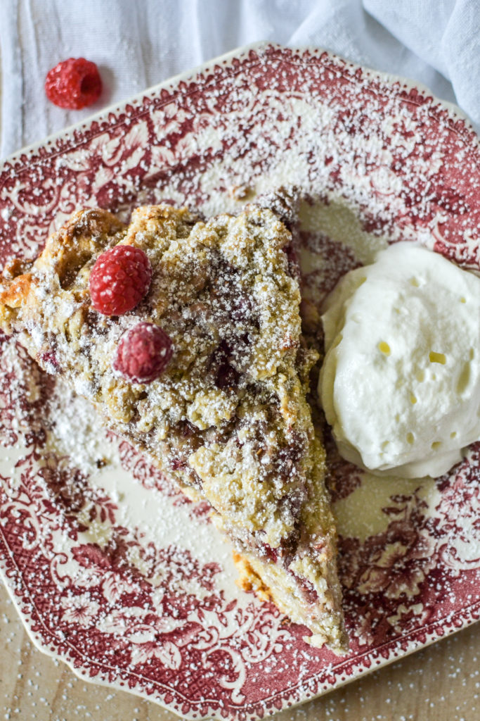 Raspberry Scone dusted with icing sugar, and a side of clotted cream.