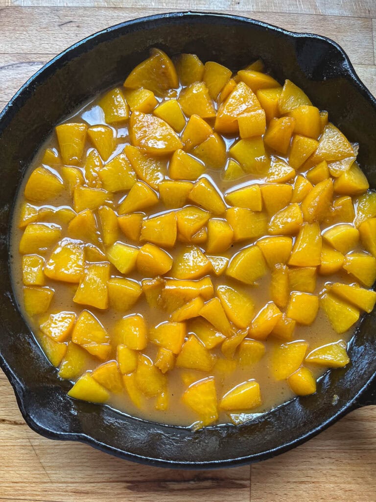 Peach sauce for peach waffles with diced peaches and a brown sugar butter sauce in a cast iron frying pan.
