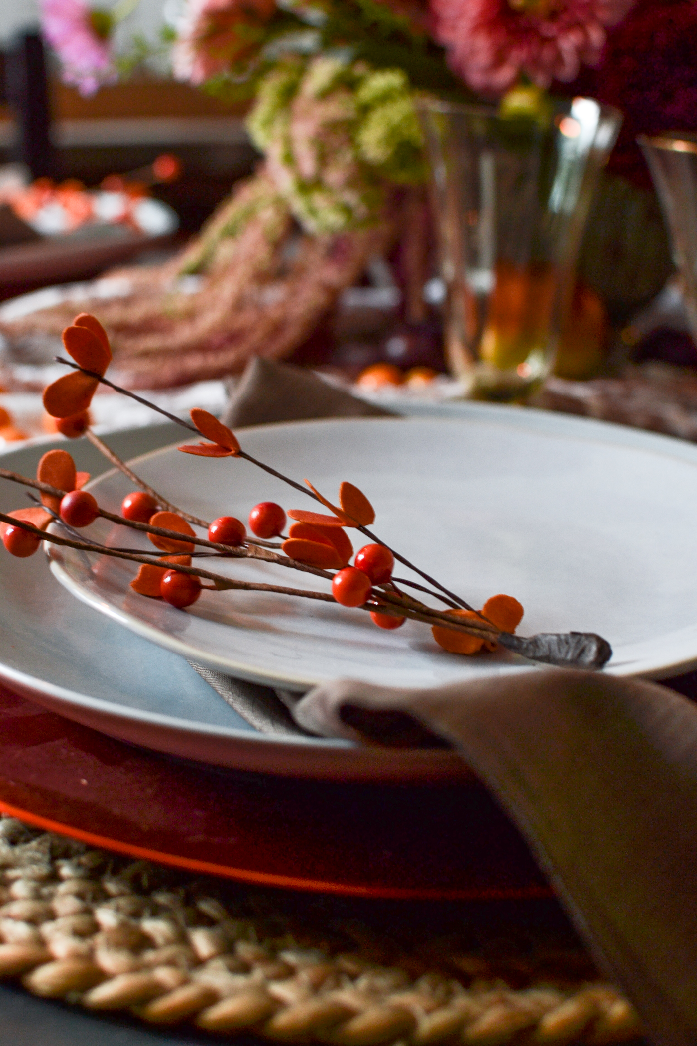 A spring of orange berries on top of a soft grey dinner plate.