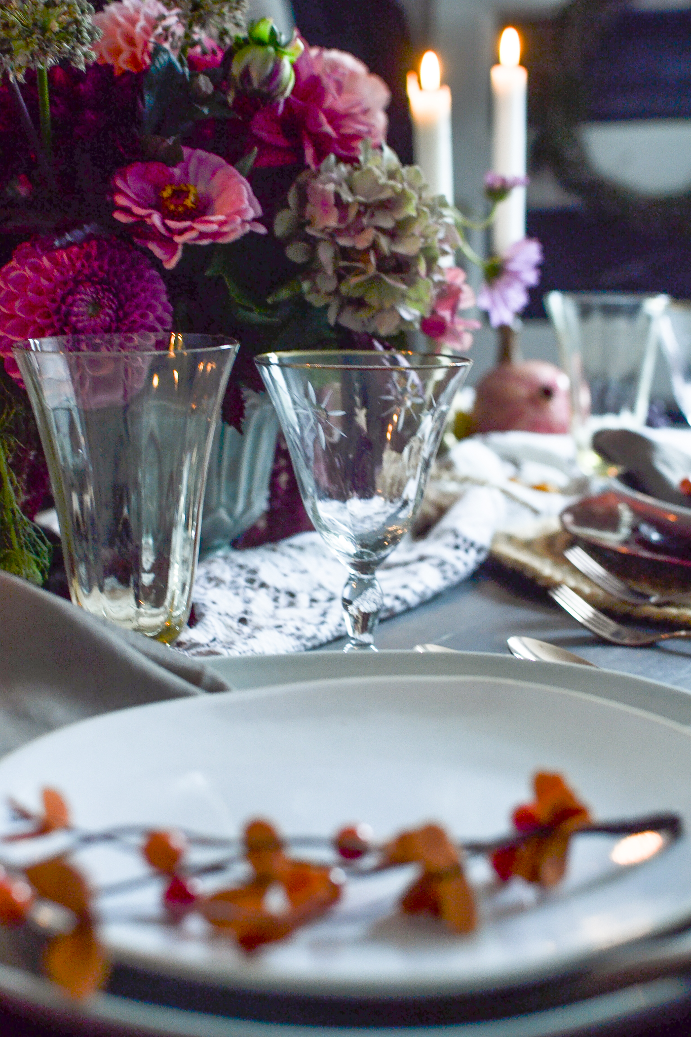 Yellow water glass and gold rimmed wine glass on a table set for dinner.