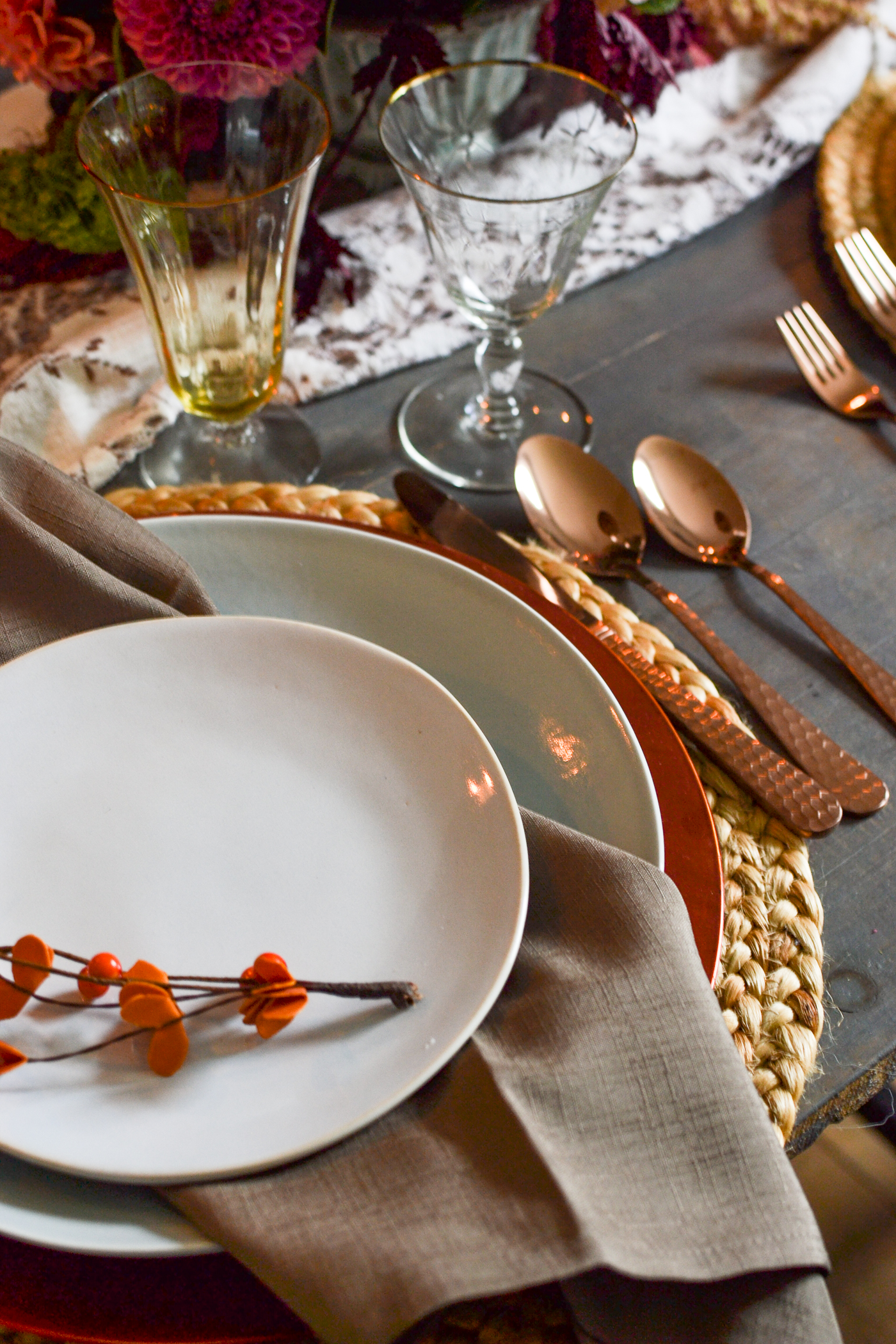 A table set with soft blue plates, brown napkins and copper flatware.