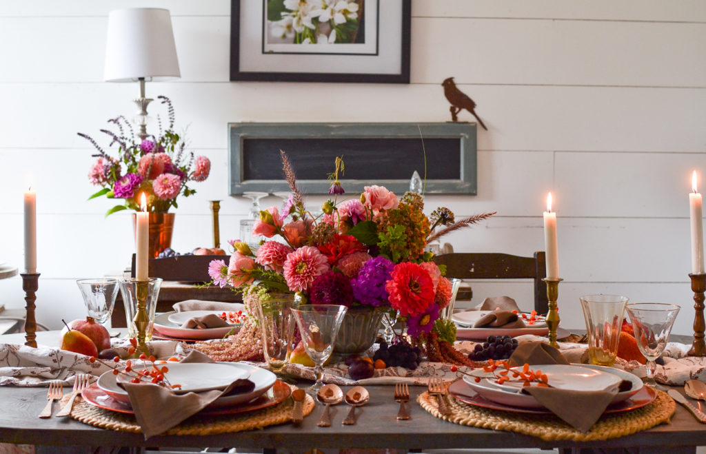 A seasonal autumn table with a dahlia centrepiece, 4 candlesticks, and blue grey plates.
