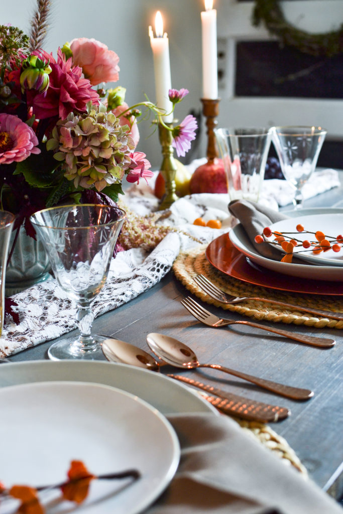 copper flatware and gold rimmed wine glasses on a fall table