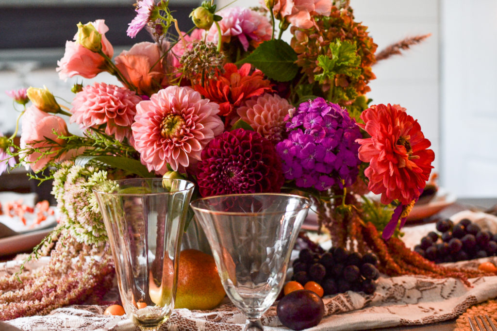 Brightly coloured autumn centrepiece made with dahlias and zinnias in shades of peach, orange, purple and pink.