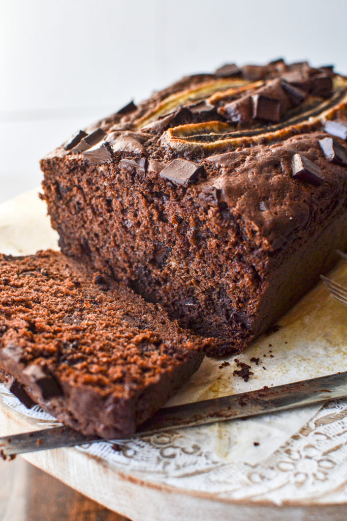 Double chocolate banana bread with sliced banana on top and one slice cut off the end