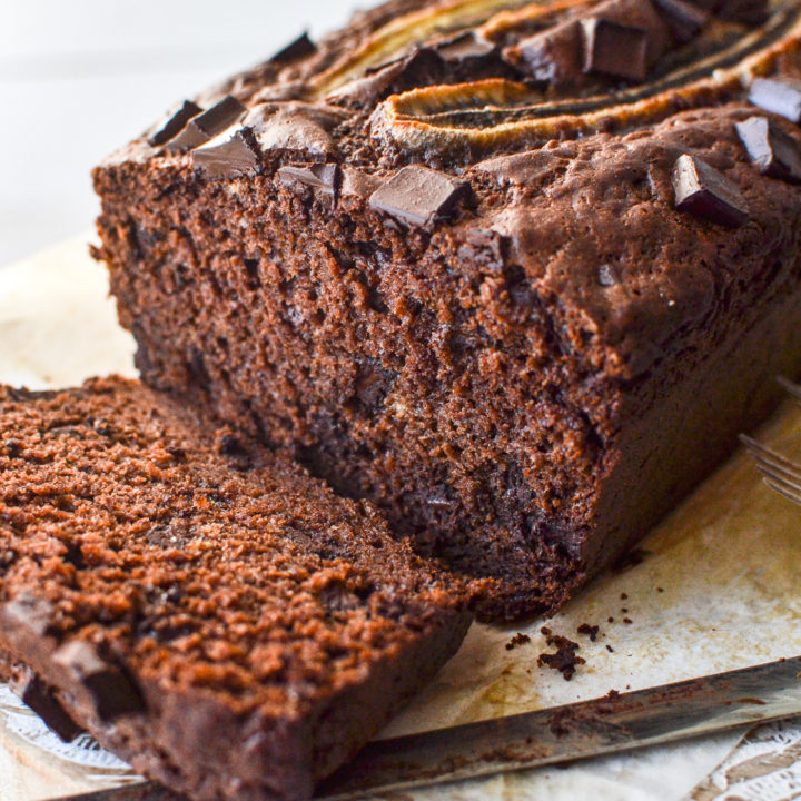 Double chocolate banana bread with sliced banana on top and one slice cut off the end