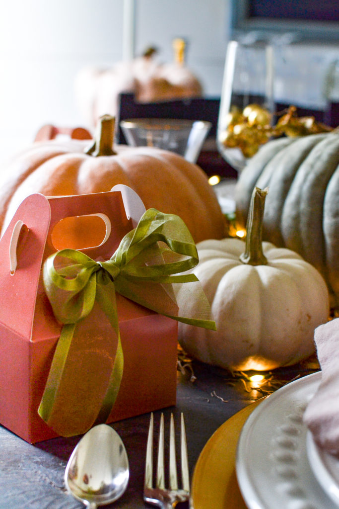 Pink treat box with a green ribbon on a Halloween dinner table