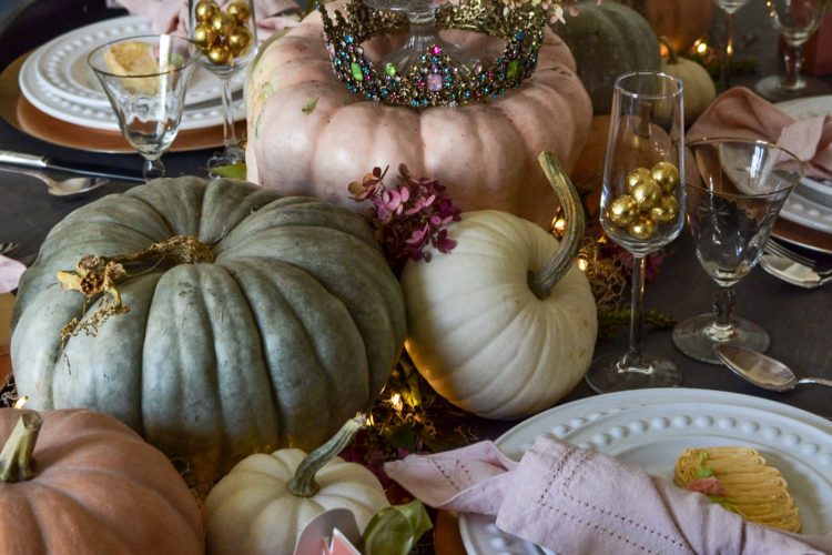 Real pumpkins in shades of pink, green, blue and white make a table runner down a dinner table styled for Halloween