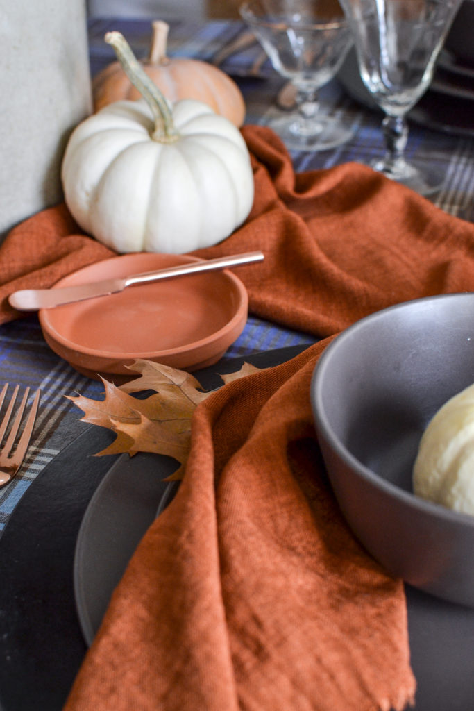 terra cotta pot saucer is used on a Thanksgiving table as a bread plate with a cooper butter knife set on top.