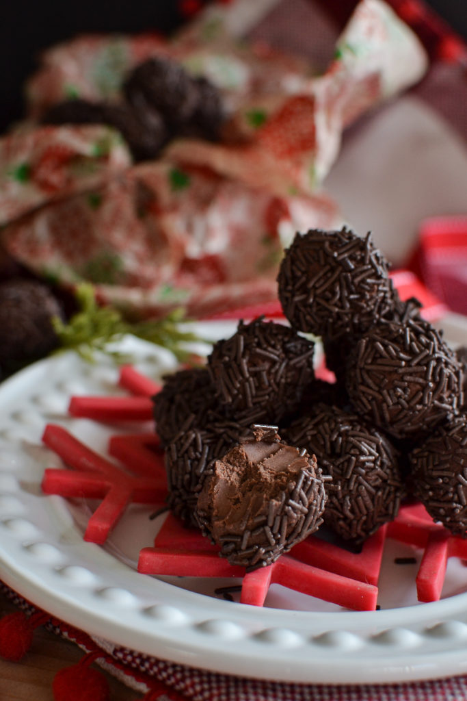 A stack of German rum balls on a white plate with a red snowflake and ribbon.