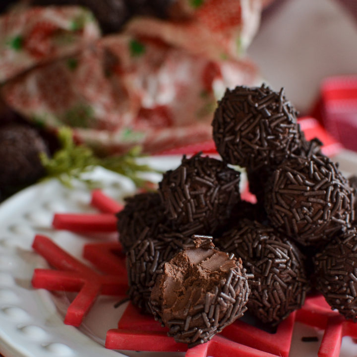 A stack of German rum balls on a white plate with a red snowflake and ribbon.