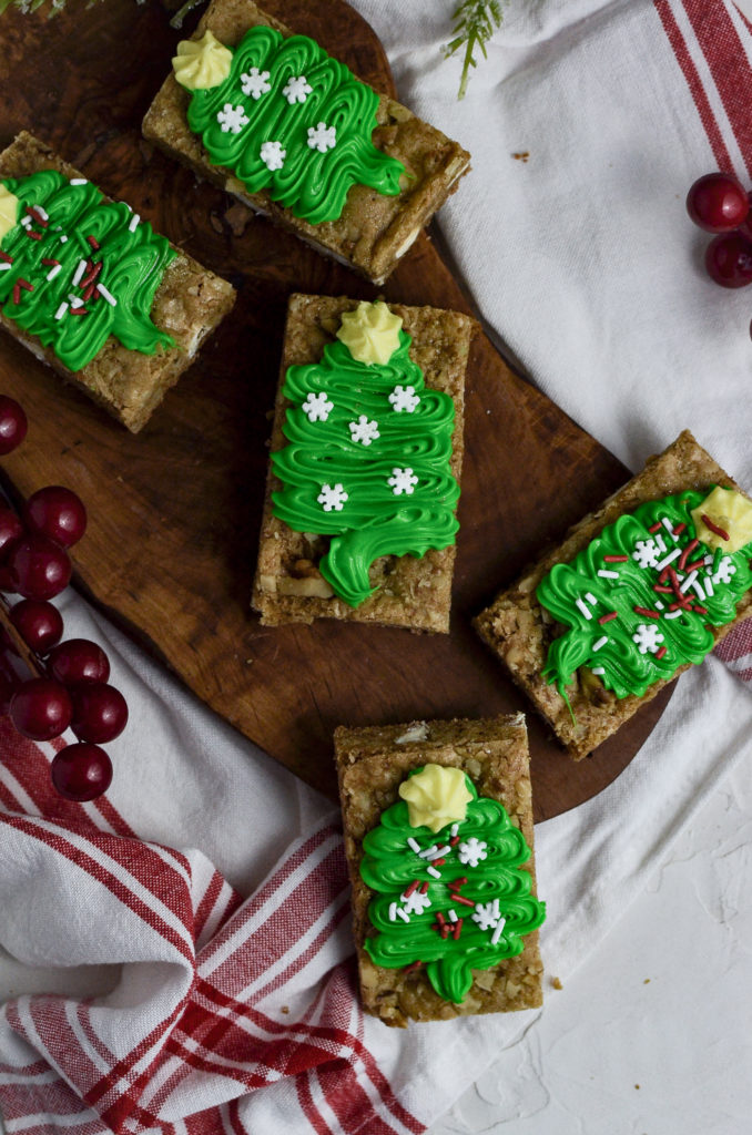 An overhead view of blondie cookies with green frosting in the shape of a Christmas tree.