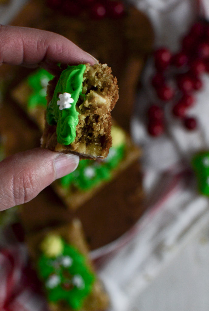 A close up of a blondie bar with a bit out of it being held between two fingers.