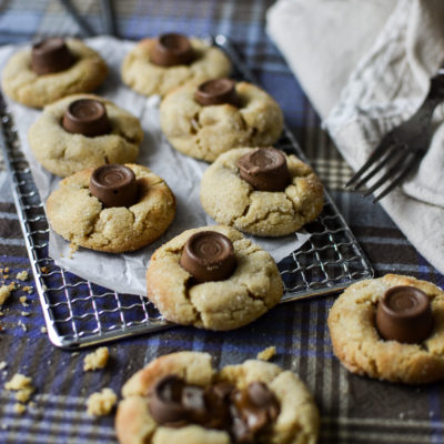 A cooling rack with freshly baked chocolate caramel peanut butter thumbprint cookies.