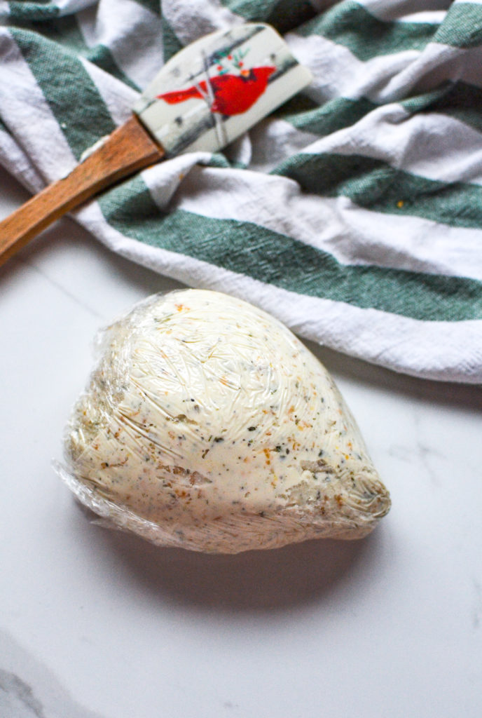 A mixture of cheeses and spices wrapped in plastic and shaped into a hedgehog