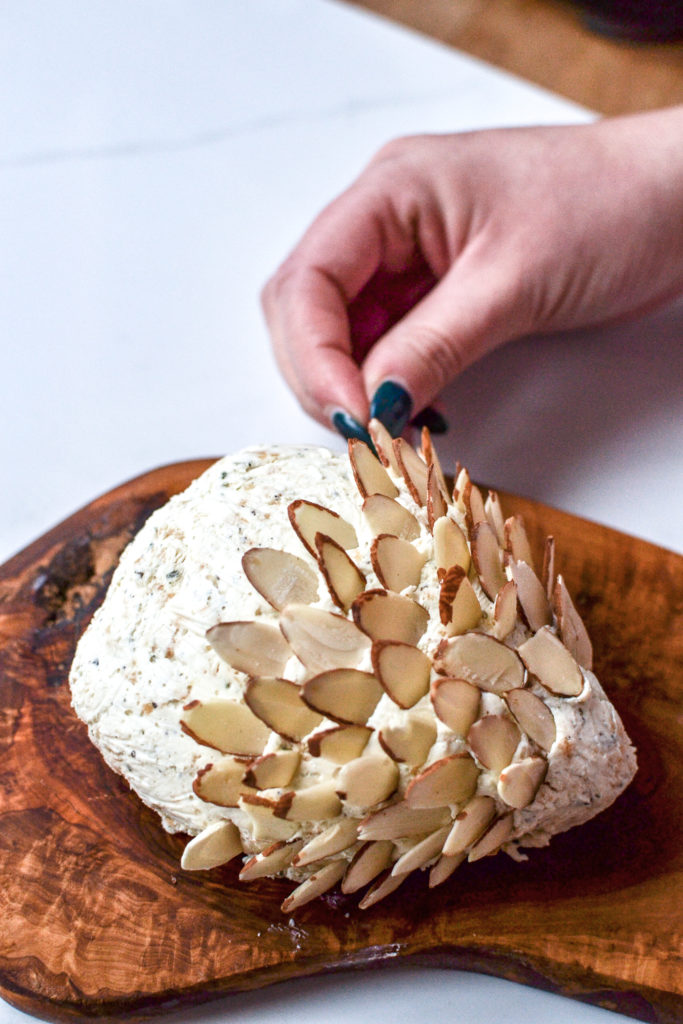 Decorating a cheese ball shaped like a hedgehog using sliced almonds