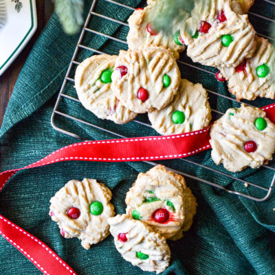 An overhead view of Peanut Butter m&m cookies on a green linen napkin with red ribbon.