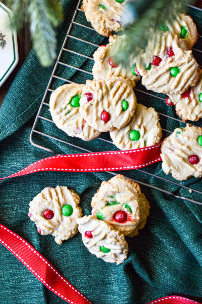 An overhead view of Peanut Butter m&m cookies on a green linen napkin with red ribbon.