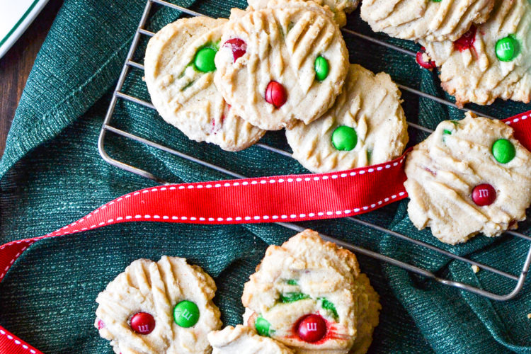 An overhead view of Peanut Butter m&m cookies on a green linen napkin with red ribbon.