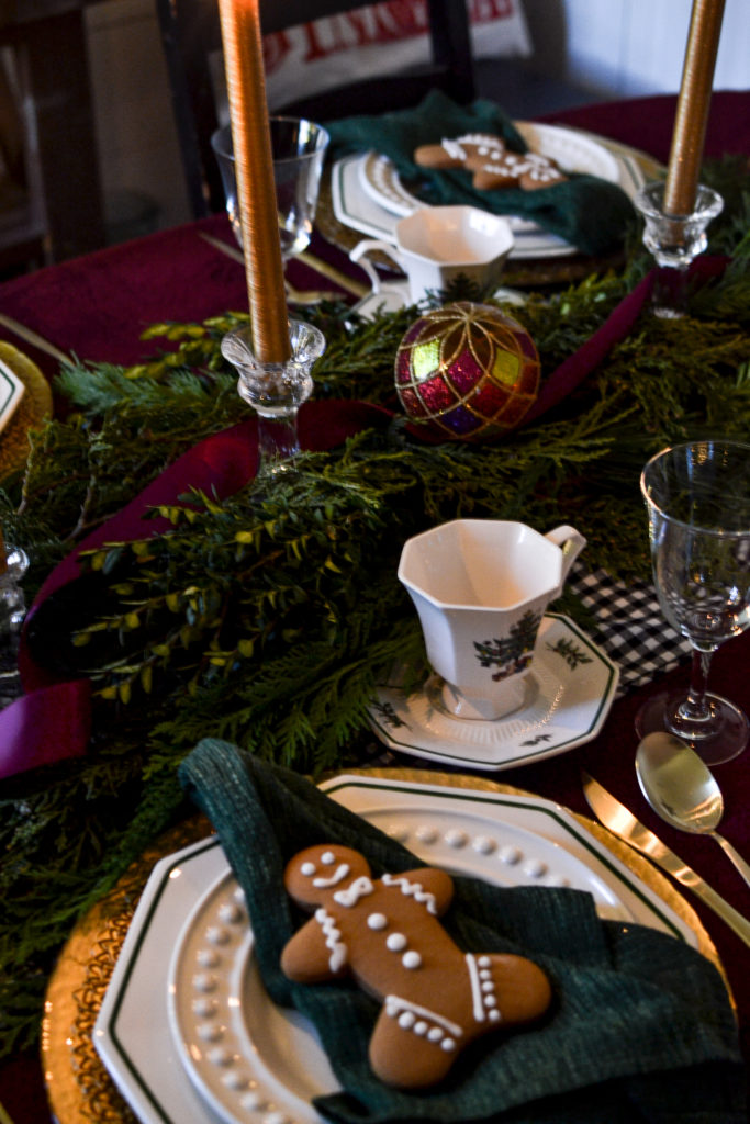 A Christmas table dimly lit with gold taper candles.