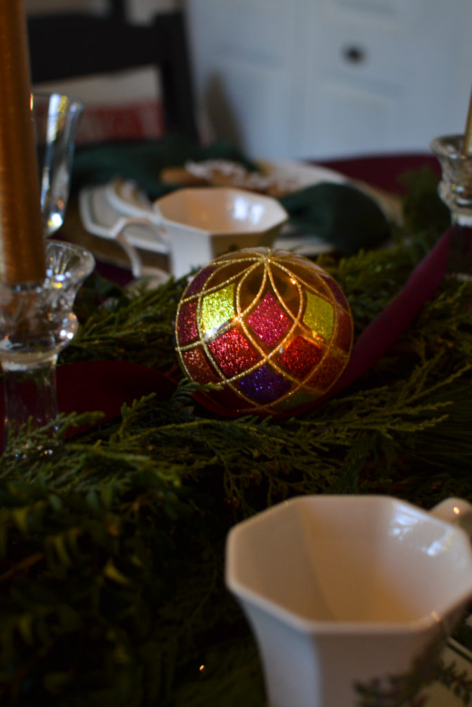 A colourful glass ornament in the centre of a table sparkles in the glow of a candle.