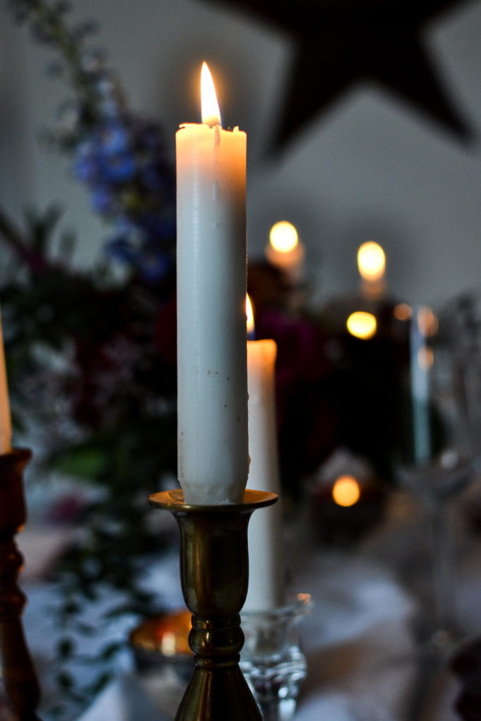 A row of lit candles on a table set for Valentine's Day