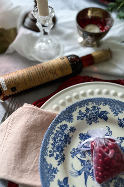 The corner of a plate stack on a valentines tablescape with a bottle of ice wine.