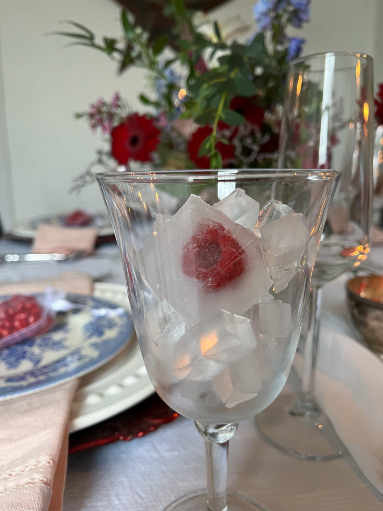 A tulip shaped wine glass filled with fruity ice cubes.