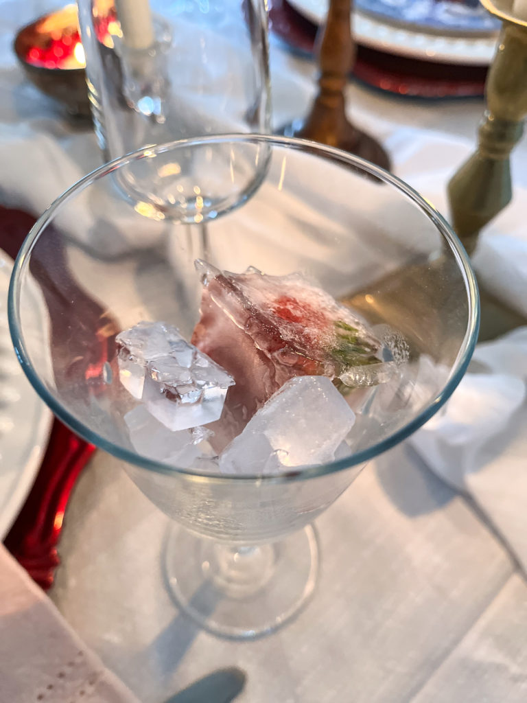 A wine glass filled with ice cubes and strawberries.