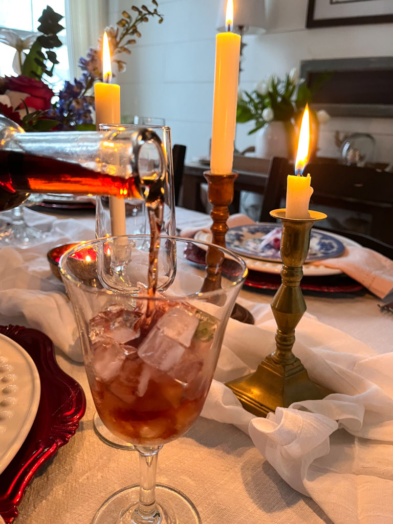 Ice wine being poured into a wine glass with candles in the background on the table.