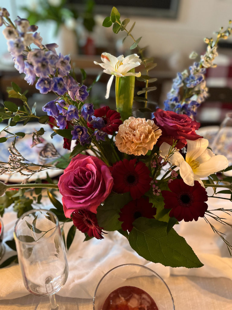 A floral centerpiece with bold coloured roses, Gerber daisies and carnations.